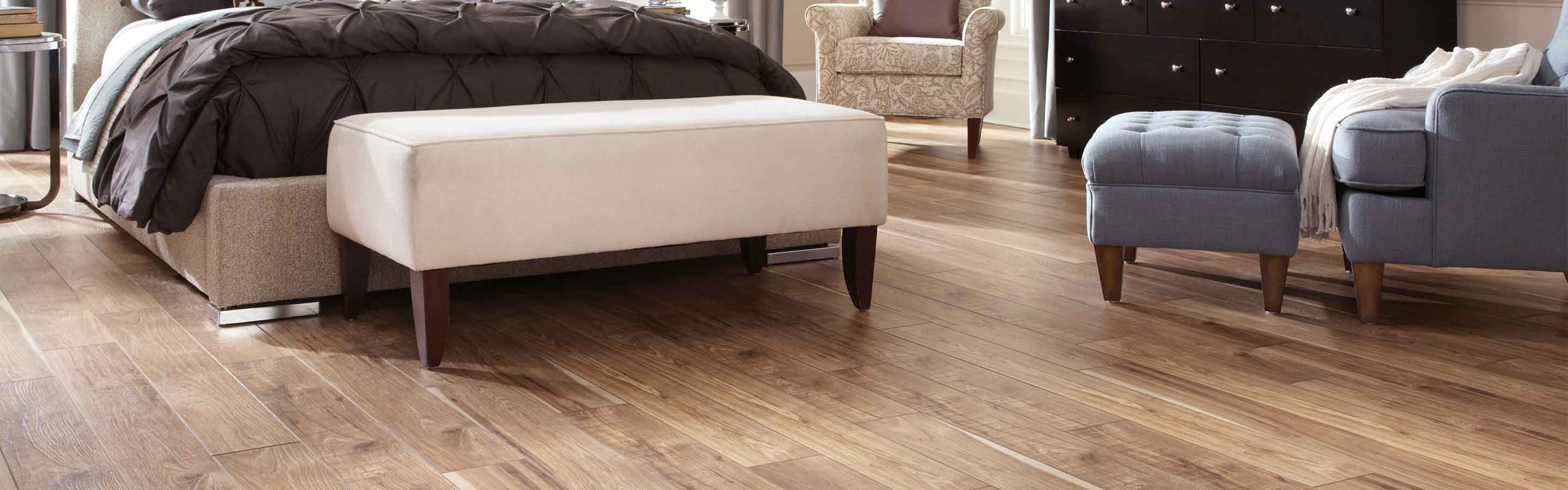 wood look laminate flooring in cozy bedroom with black dresser, chair and end of bed bench